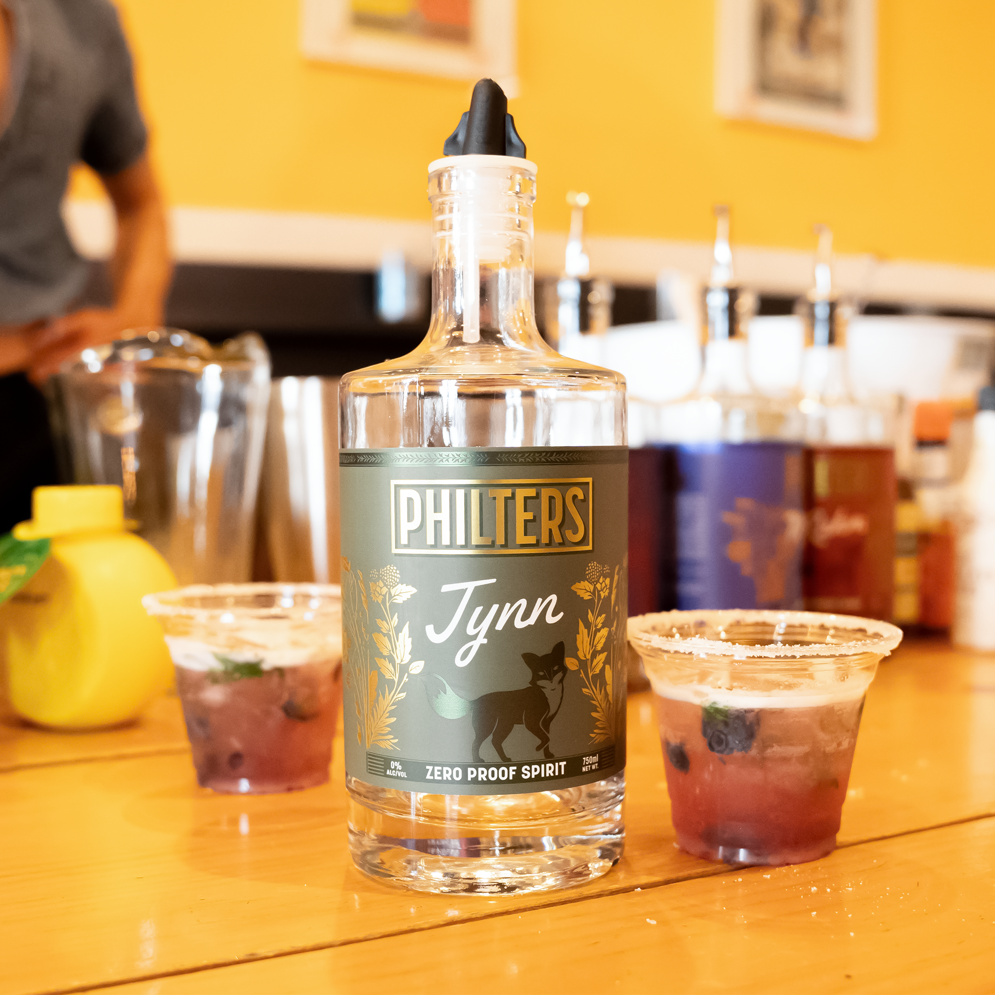Philters Jynn zero-proof botanical spirit alternative presented as a bright, aromatic ritual bottle on a refined bar cart.
